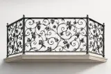 Trójstronny segment balustrady balkonowej z ręcznie kutymi detalami w postaci liści i owoców winogron.