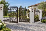 Artystyczna kuta brama wjazdowa z botanicznym ornamentem, model BU135 — aranżacja europejskiej posesji z dopasowanymi elementami ogrodzenia. Wizualizacja AI.