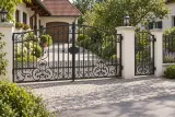 Brama kuta uchylna klasyczna z zdobieniami ornamentalnymi, model BU56 — aranżacja europejskiej posesji z dopasowanymi elementami ogrodzenia. Wizualizacja AI.