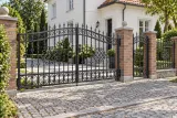 Brama wjazdowa kuta klasyczna z ornamentyką spiralną, model BU32 — aranżacja europejskiej posesji z dopasowaną furtką i przęsłem ogrodzeniowym. Wizualizacja AI.