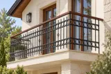Kuta balustrada balkonowa zewnętrzna z ornamentyką geometryczną i pochwytem drewnianym, model BKZ60 — aranżacja w nowej przestrzeni. Wizualizacja AI.
