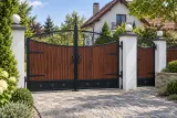 Kuta brama dwuskrzydłowa z akcentami drewnianymi i ornamentyką klasyczną, model sd129 — aranżacja europejskiej posesji z dopasowanymi elementami ogrodzenia. Wizualizacja AI.