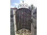 Wyrób kuty: Kuta brama posesyjna z deskowaniem drewnianym i ornamentalnymi zdobieniami
