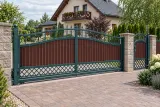 Kuta brama przesuwna z panelami drewnopodobnymi i elementami ornamentowymi, model bp31 — aranżacja europejskiej posesji z dopasowanymi elementami ogrodzenia. Wizualizacja AI.