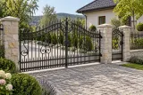 Kuta brama wjazdowa dwuskrzydłowa ze zdobieniami ornamentalnymi, model BU31 — aranżacja europejskiej posesji z dopasowaną furtką i przęsłem ogrodzeniowym. Wizualizacja AI.