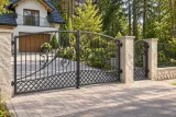 Kuta brama wjazdowa uchylna z motywami spiralnymi i kratownicą, model BU124 — aranżacja europejskiej posesji z dopasowanymi elementami ogrodzenia. Wizualizacja AI.