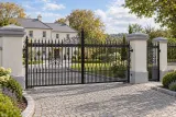 Kuta brama wjazdowa uchylna z ornamentyką klasyczną, model BU95 — aranżacja europejskiej posesji z dopasowanymi elementami ogrodzenia. Wizualizacja AI.