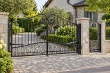 Kuta brama wjazdowa uchylna z ornamentyką liściastą, model BU99 — aranżacja europejskiej posesji z dopasowanymi elementami ogrodzenia. Wizualizacja AI.