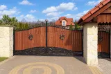 Kuta brama wjazdowa uchylna z panelami drewnianymi i ornamentyką klasyczną, model BU131 — odtworzone ujęcie oryginalne. Wizualizacja AI.