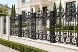 Kute ogrodzenie metalowe w stylu neobarokowym, model mg01 — aranżacja: biała willa neoklasyczna ze żwirowym dojściem i formowaną zielenią. Wizualizacja AI.