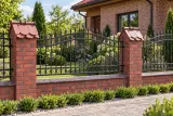Kute ogrodzenie stalowe z ornamentyką winiarską, model OK04 — aranżacja: ceglana willa z dachówką ceramiczną i zielonym ogrodem. Wizualizacja AI.