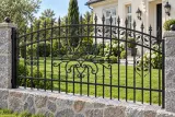 Kute przęsło ogrodzeniowe klasyczne z akcentami ornamentalnymi, model OK18 — aranżacja: kremowy dom dworkowy z granitową podmurówką i trawnikiem. Wizualizacja AI.