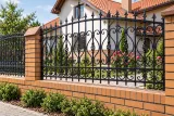 Kute przęsło ogrodzeniowe w stylu klasycznym, model OK21 — aranżacja: tradycyjny dom z ceglanym ogrodzeniem i ogrodem różanym. Wizualizacja AI.