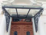 Wyrób kuty: Kuty Daszek Wejściowy ze Szklanym Panelem i Ornamentyką Kowalską