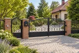 Ręcznie kuta brama wjazdowa dwuskrzydłowa z ornamentyką klasyczną, model BU52 — aranżacja europejskiej posesji z dopasowanymi elementami ogrodzenia. Wizualizacja AI.